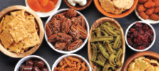 variety of shapes, sizes and colors of bowls with crackers, nuts and fruits