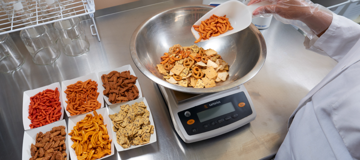 food scientist adding different snack mix components to a mix